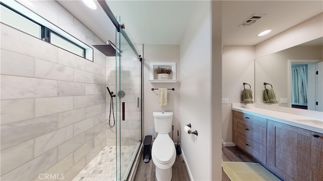 full bathroom featuring wood finished floors, visible vents, vanity, and a tile shower