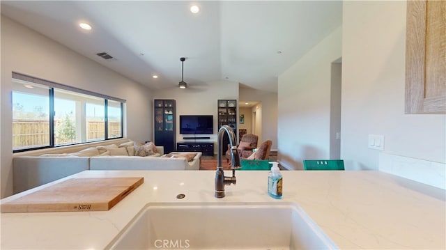 kitchen with recessed lighting, a sink, visible vents, vaulted ceiling, and open floor plan