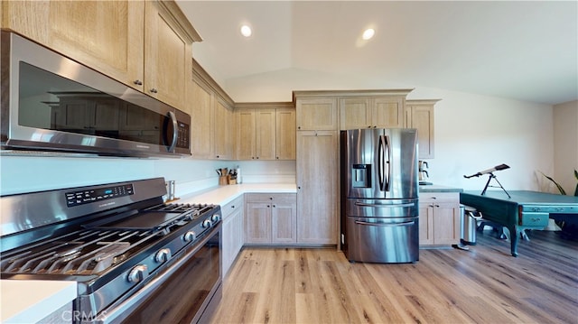 kitchen featuring light countertops, appliances with stainless steel finishes, lofted ceiling, and light wood-type flooring