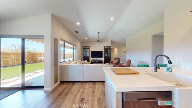 kitchen with light wood-style flooring, vaulted ceiling, dishwasher, a sink, and visible vents