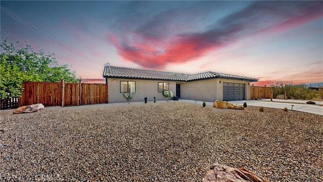 ranch-style house featuring driveway, a tiled roof, stucco siding, fence, and a garage