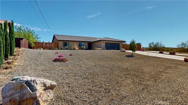 ranch-style home featuring fence, a tiled roof, stucco siding, and a garage
