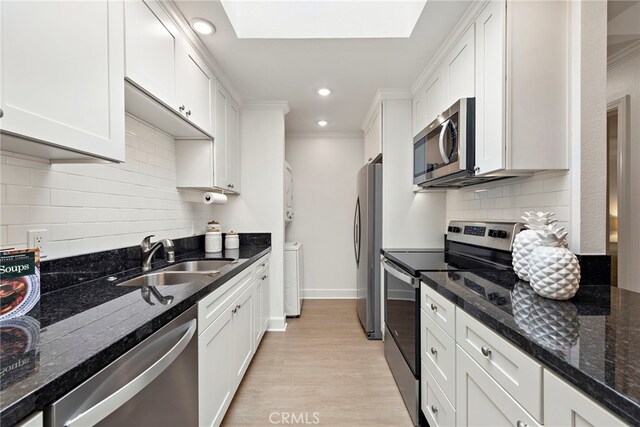 964 Calle Aragon Unit D, Laguna Woods, CA 92637 - kitchen with appliances with stainless steel finishes, a sink, white cabinets, light wood-type flooring, and dark stone counters