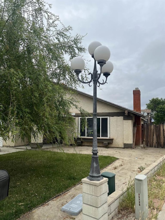 exterior space featuring stucco siding, a chimney, and fence