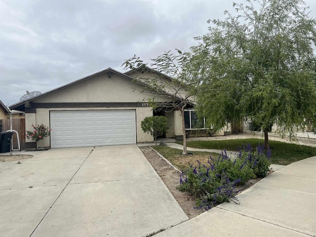 view of front of home featuring concrete driveway, a garage, stucco siding, and fence