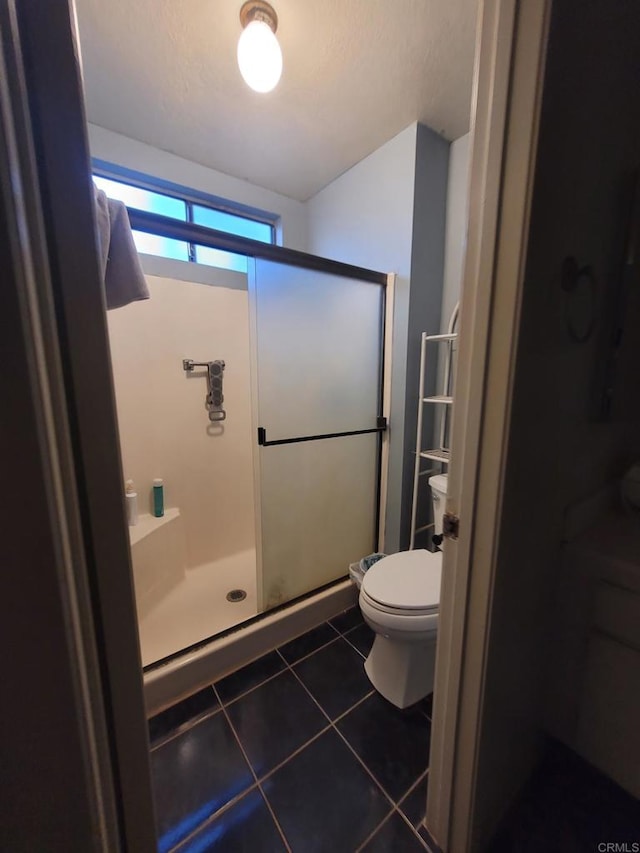 full bathroom featuring a shower stall, tile patterned floors, and toilet