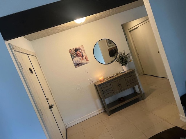 corridor with light tile patterned floors and baseboards