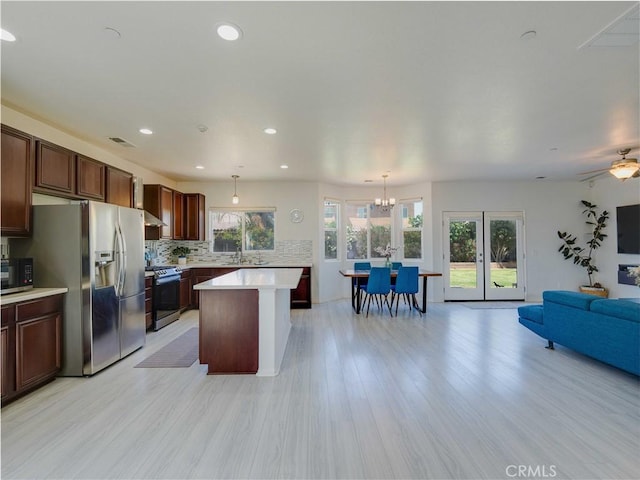 kitchen featuring stainless steel appliances, visible vents, backsplash, light countertops, and open floor plan