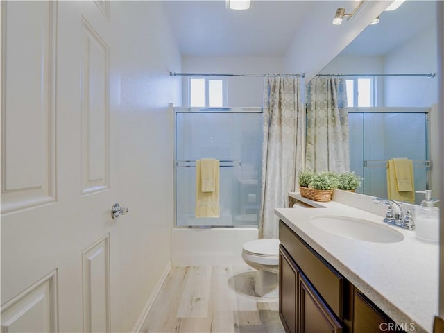 full bathroom with wood finished floors, shower / bath combo, toilet, vanity, and baseboards