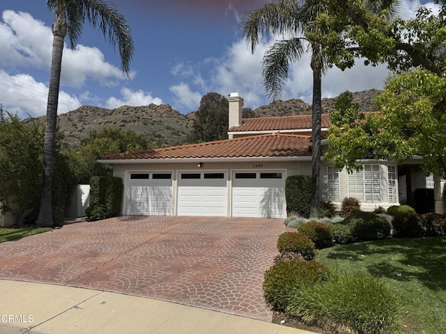 1480 Forest Knoll Dr, Oak Park, CA 91377 - view of front facade with a tiled roof, a chimney, decorative driveway, a mountain view, and an attached garage