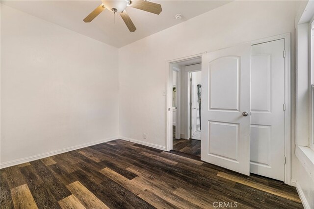 unfurnished bedroom featuring baseboards, ceiling fan, and dark wood-type flooring