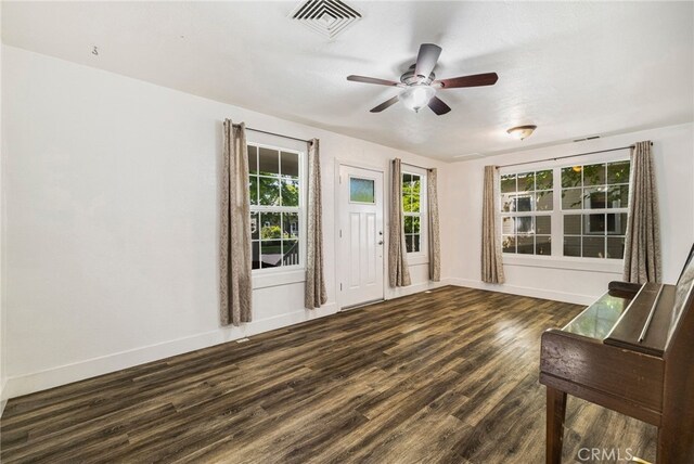 interior space featuring visible vents, a ceiling fan, baseboards, and dark wood-type flooring