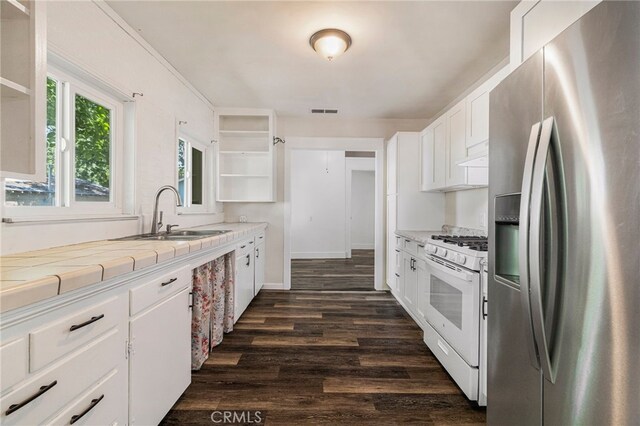 kitchen featuring open shelves, white gas range, tile counters, stainless steel fridge with ice dispenser, and a sink
