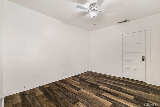 spare room featuring a ceiling fan, baseboards, visible vents, and dark wood-type flooring