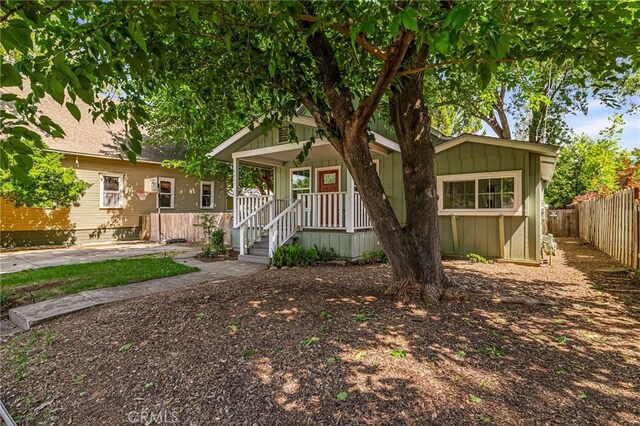 view of front facade featuring a porch, fence, and board and batten siding