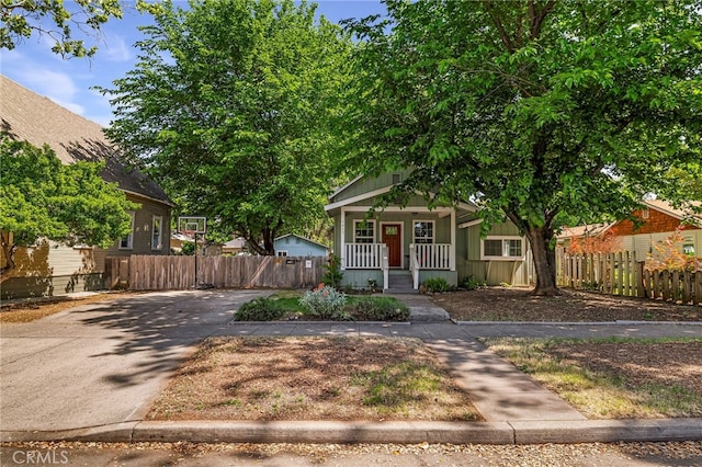 bungalow-style home featuring fence, covered porch, and driveway