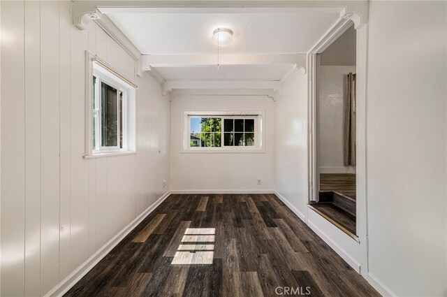 hallway with baseboards, wood finished floors, and beam ceiling