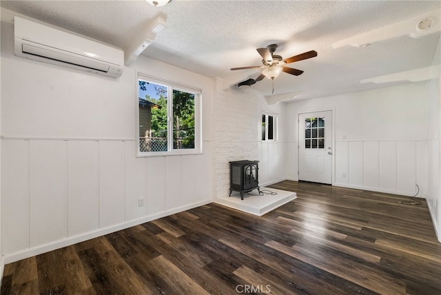 1617 Hemlock St, Chico, CA 95928 - unfurnished living room with a wall mounted air conditioner, a wood stove, a textured ceiling, ceiling fan, and a wainscoted wall