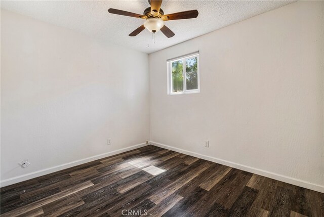 unfurnished room with a ceiling fan, baseboards, a textured ceiling, and dark wood-type flooring