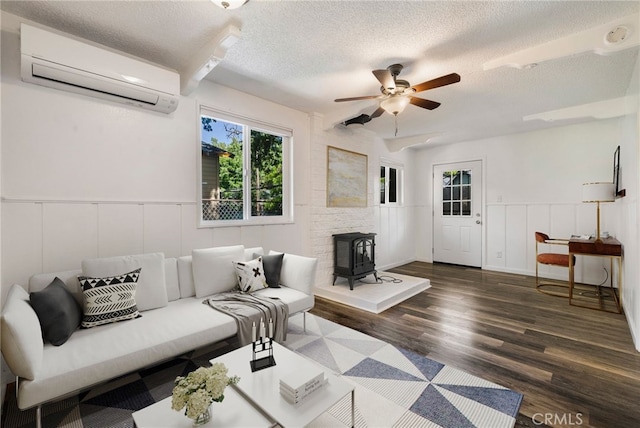 1617 Hemlock St, Chico, CA 95928 - living room featuring an AC wall unit, a wood stove, a textured ceiling, a ceiling fan, and wood finished floors