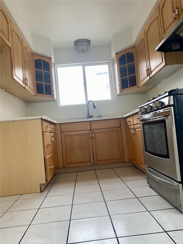 kitchen featuring light tile patterned floors, gas range, under cabinet range hood, light countertops, and a sink