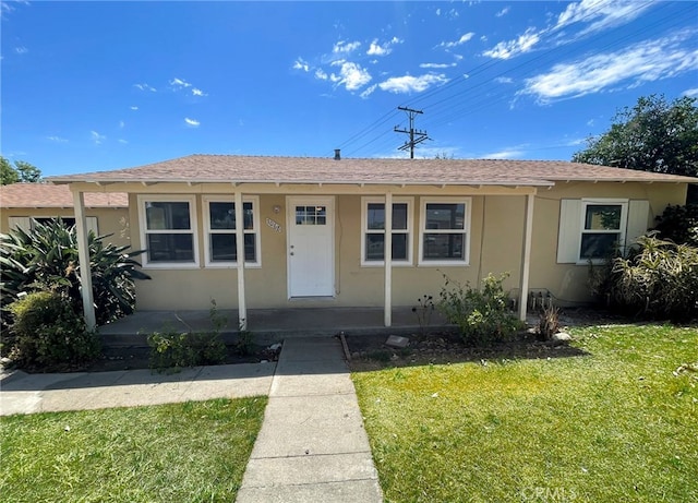 single story home featuring stucco siding, a porch, a shingled roof, and a front lawn