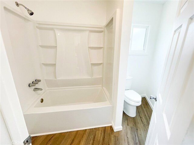 full bathroom featuring baseboards, wood finished floors, toilet, and shower / bathing tub combination