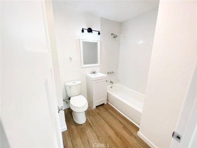 bathroom featuring wood finished floors, toilet, shower / washtub combination, and vanity
