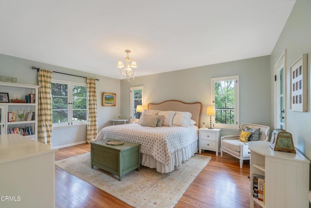 bedroom with baseboards, wood finished floors, and a notable chandelier
