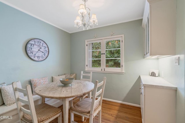 dining area with an inviting chandelier, breakfast area, crown molding, baseboards, and wood finished floors
