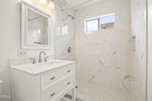 full bath featuring a marble finish shower and vanity