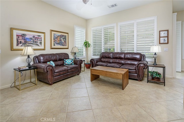 living room featuring light tile patterned flooring, visible vents, ceiling fan, and baseboards