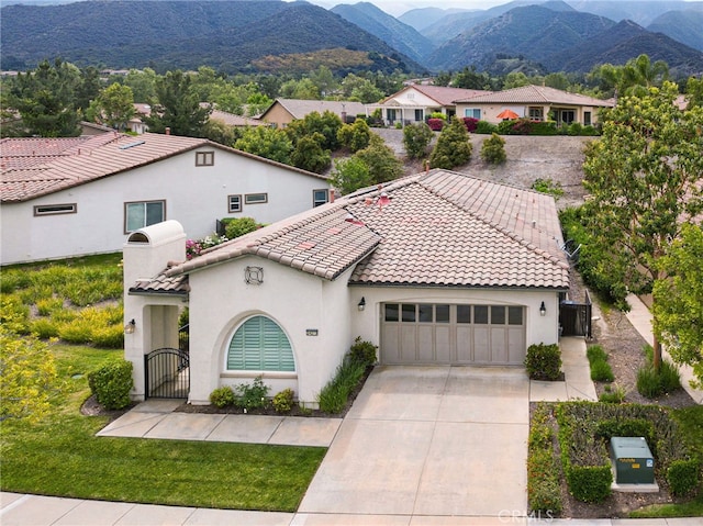 mediterranean / spanish-style house with concrete driveway, an attached garage, a tiled roof, and a gate