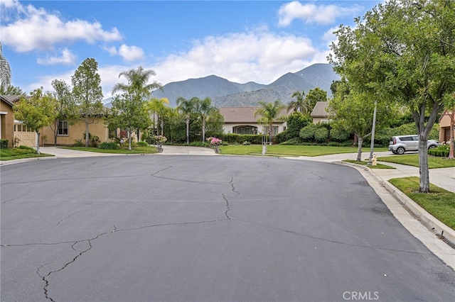 view of street with curbs, a mountain view, a residential view, and sidewalks