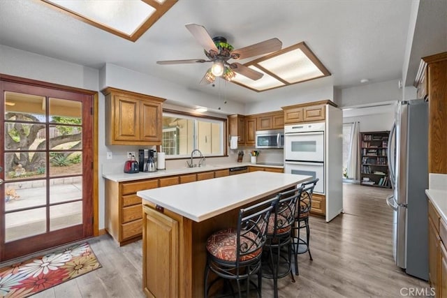 259 Saint Andrews Way, Lompoc, CA 93436 - kitchen featuring appliances with stainless steel finishes, a kitchen bar, light countertops, a kitchen island, and light wood finished floors