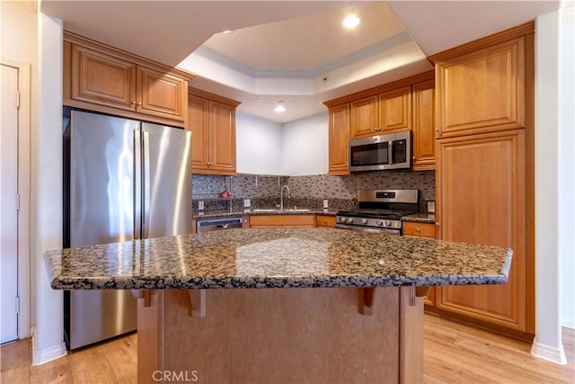 1437 Lomita Blvd Unit 227, Harbor City, CA 90710 - kitchen with appliances with stainless steel finishes, a sink, a raised ceiling, light wood finished floors, and a breakfast bar