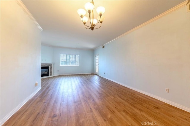 1437 Lomita Blvd Unit 227, Harbor City, CA 90710 - unfurnished living room featuring crown molding, wood finished floors, baseboards, an inviting chandelier, and a premium fireplace