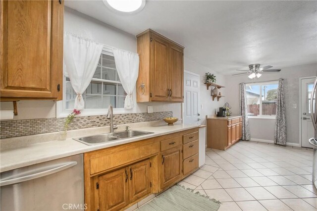 kitchen featuring tasteful backsplash, light countertops, stainless steel dishwasher, and a sink