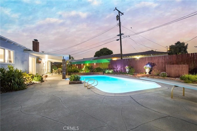 view of swimming pool with a diving board, a fenced backyard, a fenced in pool, and a patio area