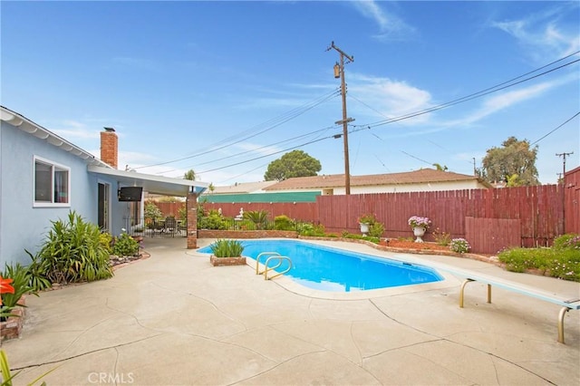 view of swimming pool featuring a patio, a diving board, a fenced backyard, and a fenced in pool