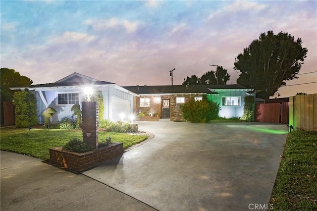 ranch-style home featuring fence, a front lawn, concrete driveway, and an attached garage