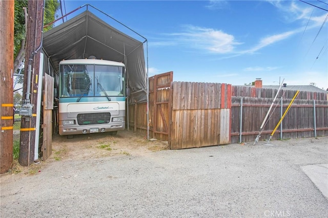 view of vehicle parking with fence and a detached carport