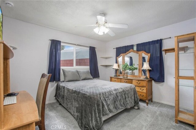bedroom featuring baseboards, light carpet, a textured ceiling, and ceiling fan