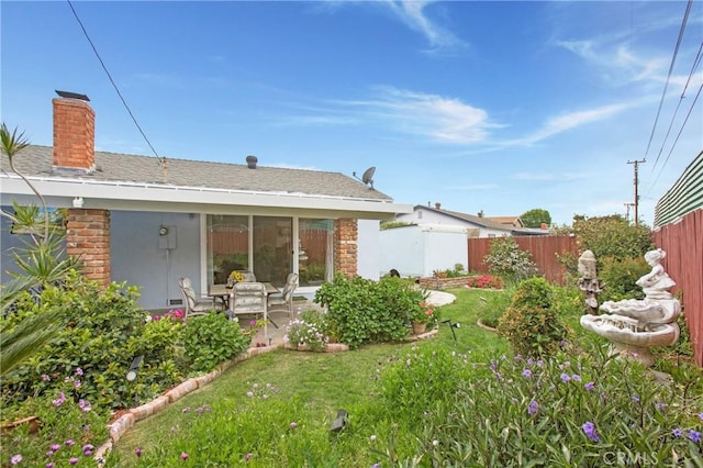 rear view of property with a patio, stone siding, a chimney, a lawn, and fence