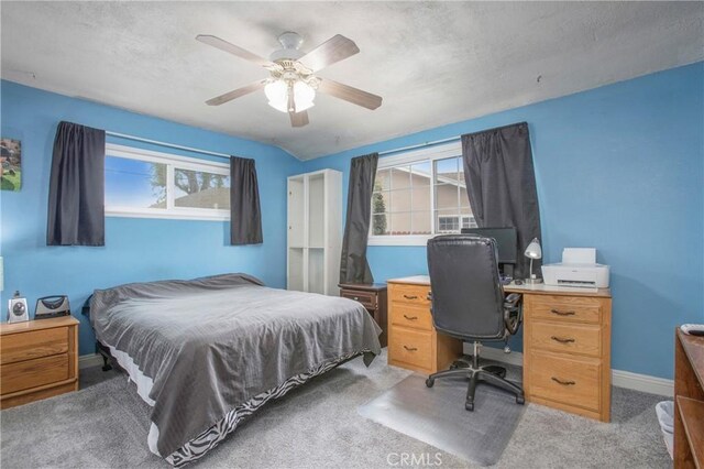 bedroom featuring multiple windows, ceiling fan, light colored carpet, and baseboards
