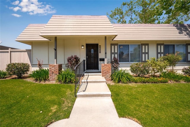 view of front of home featuring fence and a front lawn