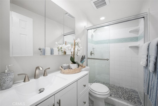 full bathroom with vanity, a stall shower, toilet, and visible vents