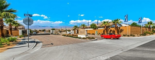 view of road featuring a gate, curbs, a gated entry, a mountain view, and traffic signs