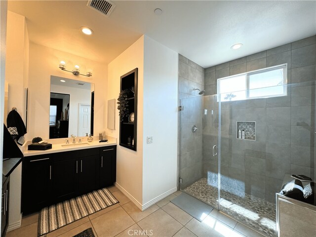 bathroom featuring tile patterned flooring, a shower stall, vanity, baseboards, and visible vents
