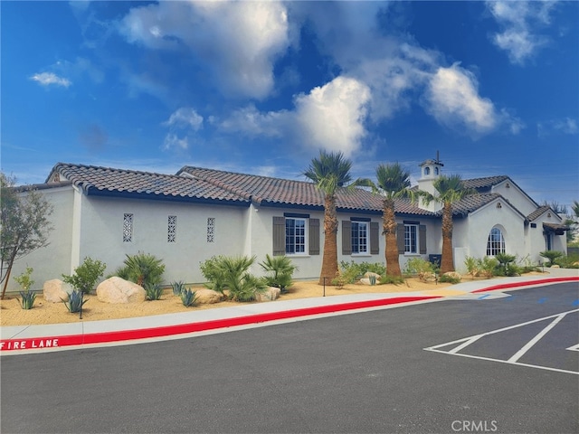view of front of home with uncovered parking, stucco siding, and a tile roof